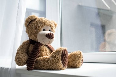 close up view of cute teddy bear on window sill 