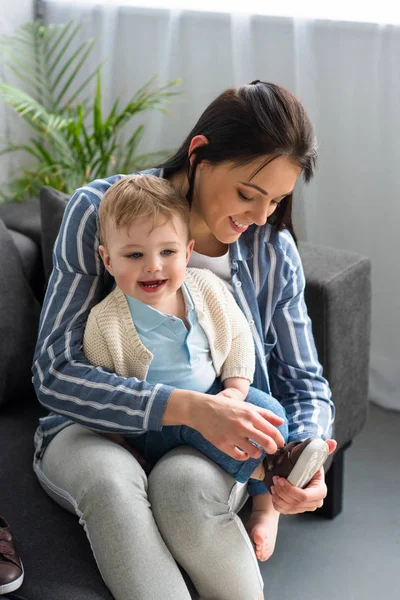 Mother Dressing Cheerful Little Baby Sofa Home — Stock Photo, Image