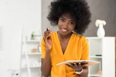 ev ofis, defter ile gülümseyen Afro-Amerikan freelancer portresi