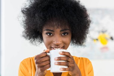 Evde kahve ile gülümseyen Afrikalı-Amerikalı kadın portresi