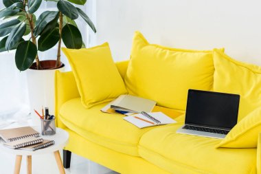 Sarı kanepe evde dizüstü bilgisayar, dizüstü bilgisayarlar ve klasörler görünümü kadar office kapatın