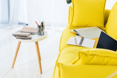 Sarı kanepe evde dizüstü bilgisayar, dizüstü bilgisayarlar ve klasörler görünümü kadar office kapatın