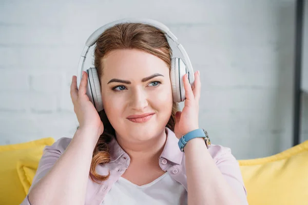 Όμορφη Γυναίκα Ακούγοντας Μουσική Στον Καναπέ Και Βλέπει Μακριά Στο — Φωτογραφία Αρχείου