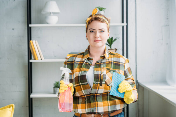 beautiful woman showing spray bottle and rag for cleaning at home