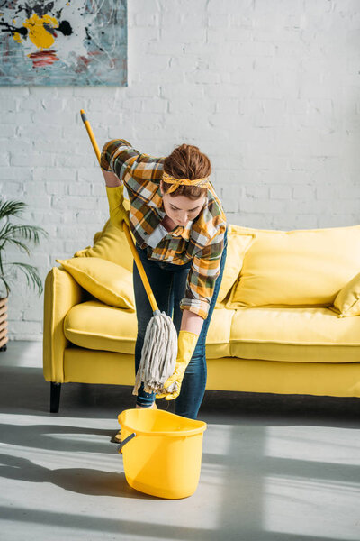 beautiful woman wringing out rag on mop at home