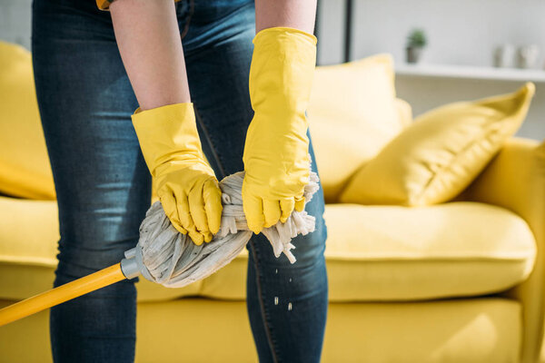 beautiful woman wringing out rag on mop at home