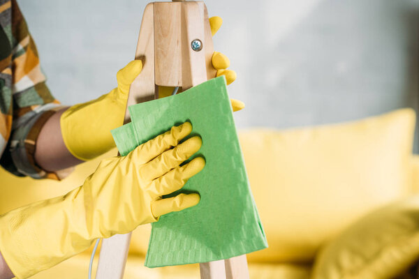 cropped image of woman dusting furniture with rag at home
