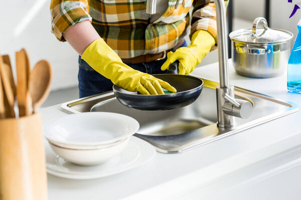 cropped image of woman washing frying pan in kitchen