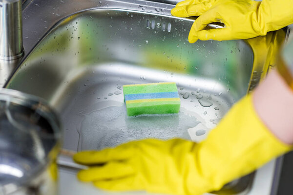 cropped image of woman cleaning sink in kitchen