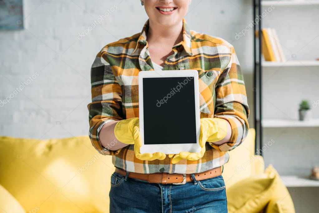 Cropped image of woman in cleaning gloves showing tablet at home
