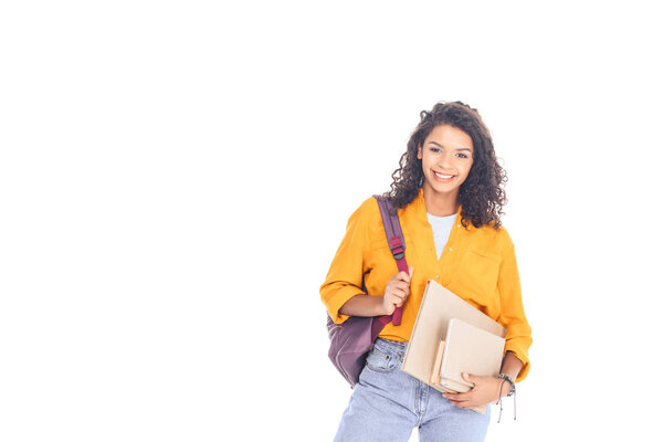 портрет улыбающегося африканского студента с рюкзаком и книгами, изолированными на белом
