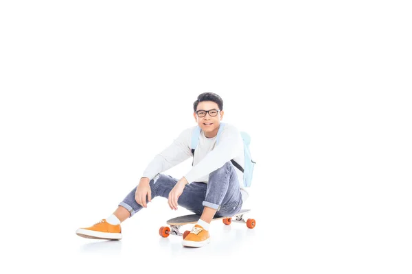 Asiatiska Tonåring Med Ryggsäck Sitter Skateboard Isolerad Vit — Stockfoto