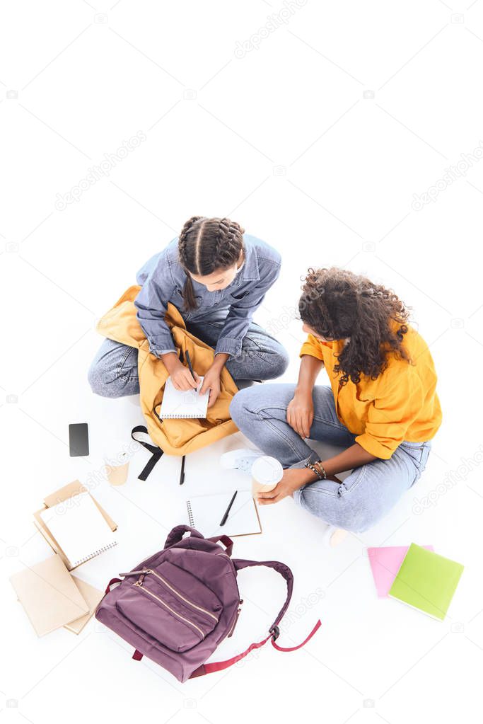 overhead view of multiethnic students doing homework together isolated on white
