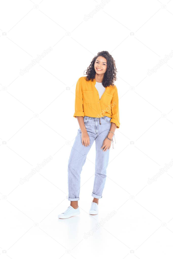 smiling african american teenager with curly hair posing isolated on white