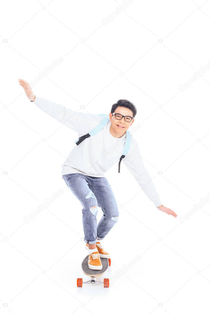 asian teenager with backpack riding skateboard isolated on white