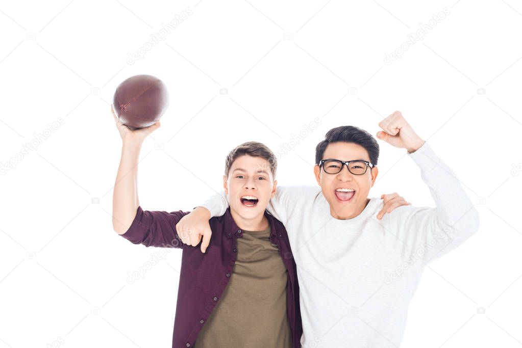 portrait of cheerful interracial teen boys with rugby ball isolated on white