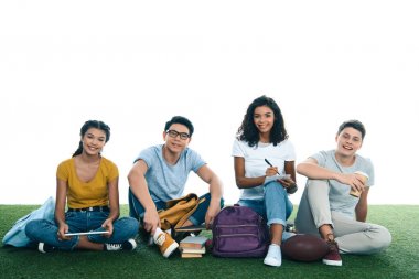 Grup genç öğrenci çim üzerinde oturan beyaz izole iken eğitim