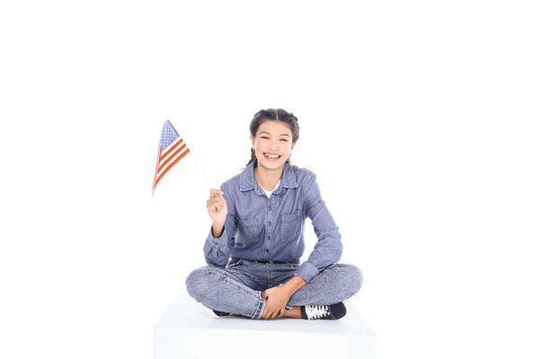 teenage student girl sitting on floor and looking at camera with usa flag isolated on white