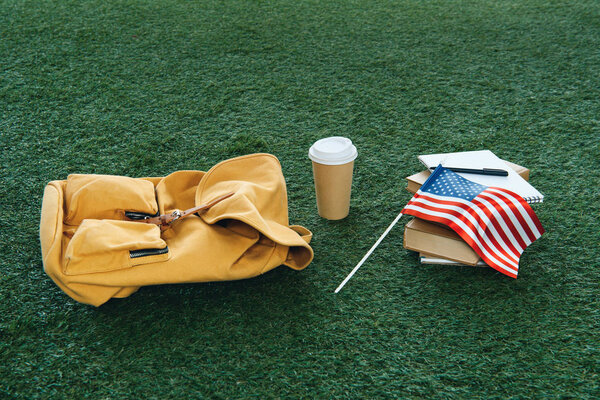 vintage backpack and school supplies with usa flag on green grass