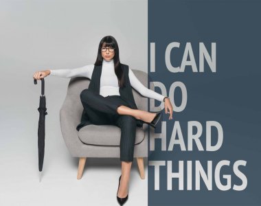 beautiful brunette businesswoman sitting on armchair with umbrella on gray with you can do hard things clipart
