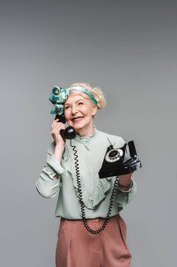happy senior woman talking by rotary phone isolated on grey clipart