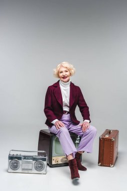 mutlu kadın kıdemli Vintage üzerinde oturan gri televizyonda