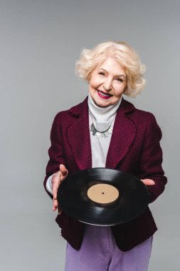 Vinil disk üzerinde gri arka plan izole tutan şık üst düzey kadın 