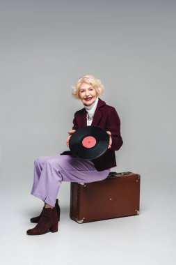 kadın vintage çanta gri arka plan üzerinde oturan vinil disk ile kıdemli mutlu şık 