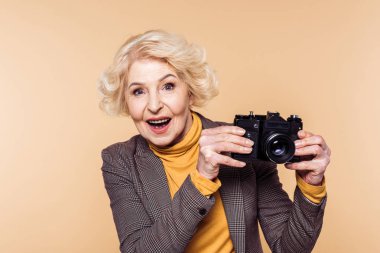 bej renkli arka plan üzerinde izole film kamera ile sürpriz üst düzey kadın 