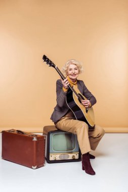 akustik gitar vintage üzerinde oturan kadın kıdemli tv yakınındaki eski çanta 