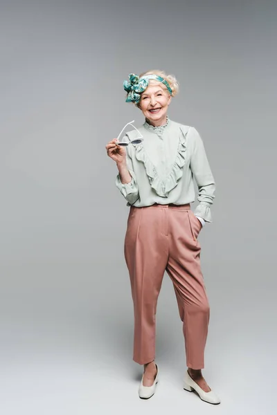 Beautiful Senior Woman Stylish Clothes Holding Sunglasses Grey — Free Stock Photo