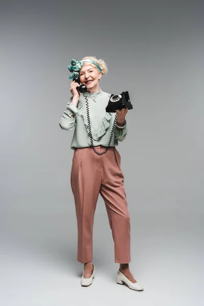 グレーのダイヤル式電話で話して幸せな年配の女性 — ストック写真