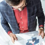 Vista de ángulo alto del joven empresario leyendo el periódico en la oficina