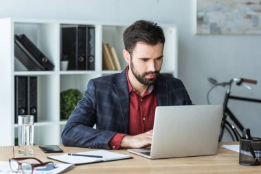 laptop ile ofiste çalışan yakışıklı genç işadamı