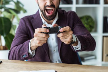 genç işadamı gamepad ile oyun oynarken bağırarak in atış kırpılmış