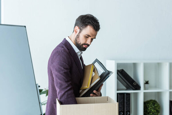 fired young businessman putting books and folders into box