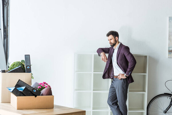 thoughtful fired businessman leaning on shelves at office
