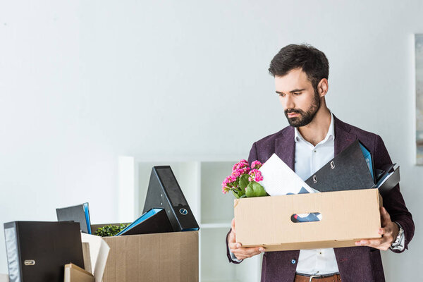 fired young businessman with boxes of personal stuff in office