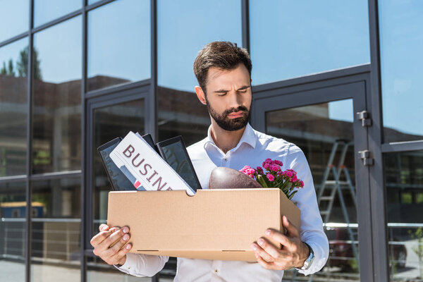 handsome manager with box of personal stuff outdoors after he was fired