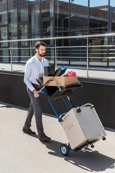 fired young manager with boxes on trolley cart 