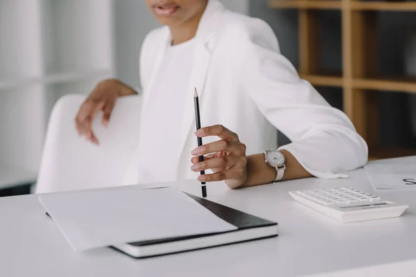 Imagen Recortada Mujer Negocios Afroamericana Sentada Mesa Sosteniendo Lápiz Oficina —  Fotos de Stock