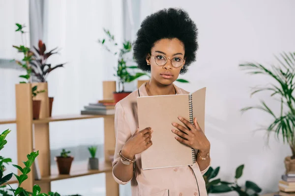 Atractiva Mujer Negocios Afroamericana Sosteniendo Portátil Mirando Cámara Oficina — Foto de stock gratis