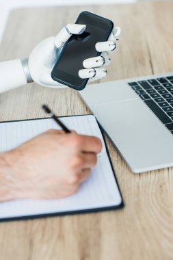 Robotik Kol smartphone ve insan eli not almak ahşap masa tutarak yakından görmek