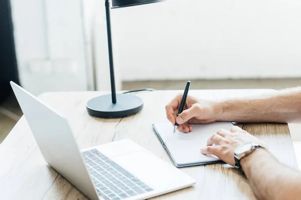 Recortado Tiro Persona Tomando Notas Trabajando Con Ordenador Portátil Mesa — Foto de Stock