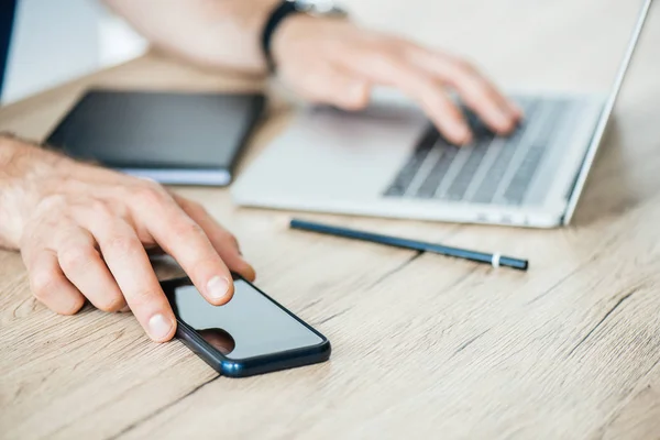 Cropped Shot Person Holding Smartphone Using Laptop Wooden Table — Stock Photo, Image