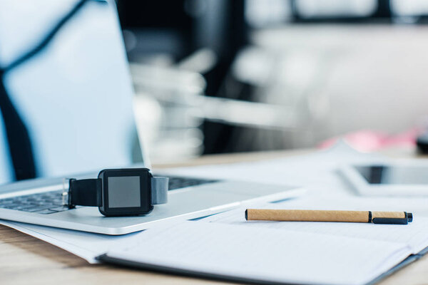 close-up view of smartwatch, laptop and notebook at workplace 