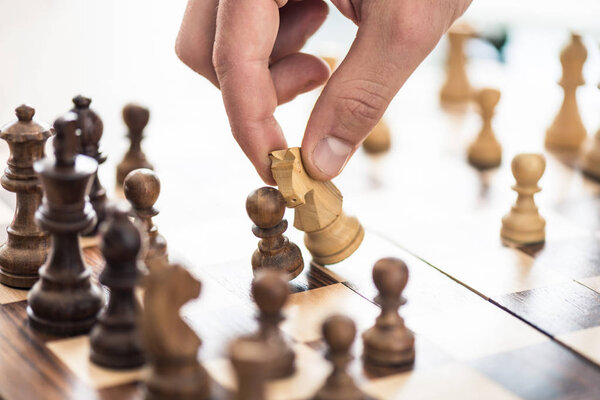 close-up partial view of human hand playing chess 