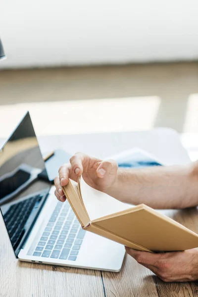 Schnappschuss Von Person Die Buch Tisch Mit Laptop Hält — Stockfoto