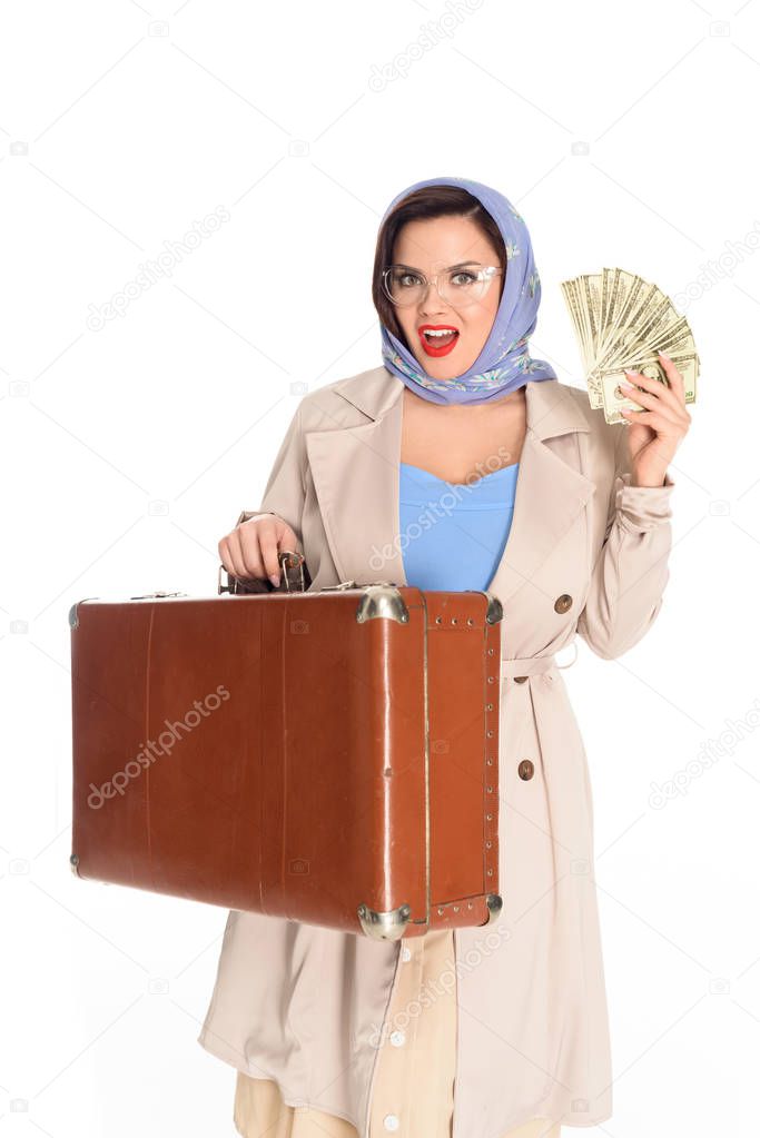beautiful young vintage woman in eyeglasses holding suitcase and dollar banknotes isolated on white