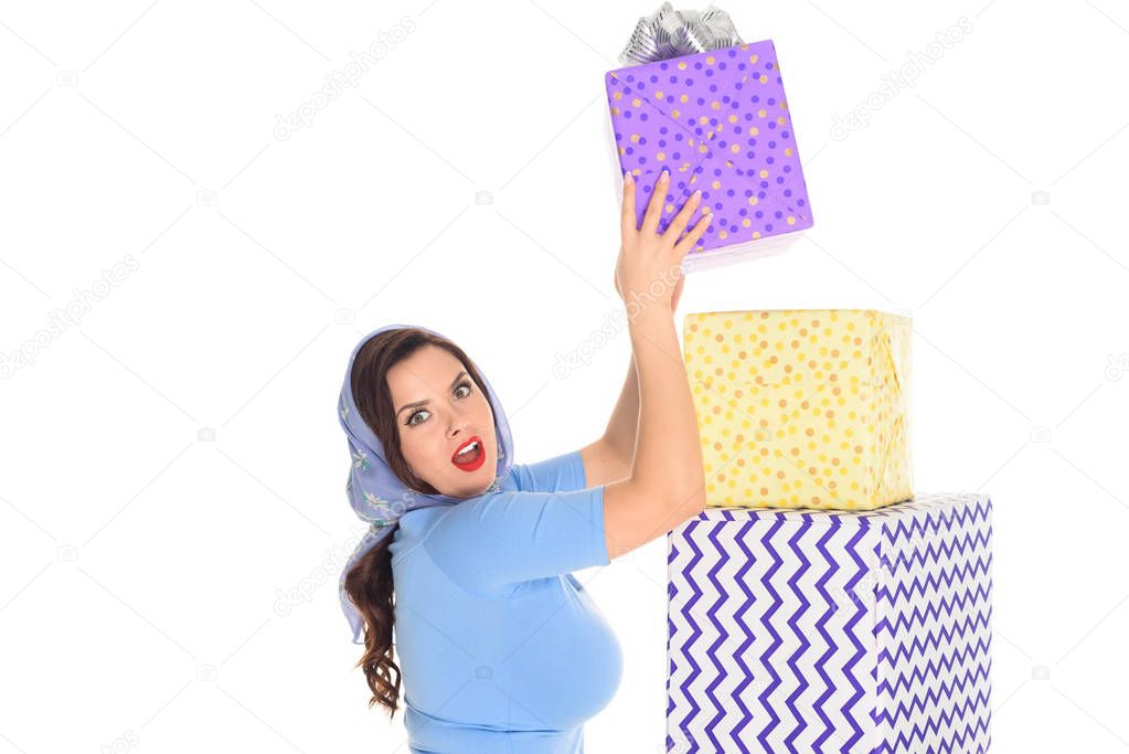 surprised young woman with pile of presents looking at camera isolated on white